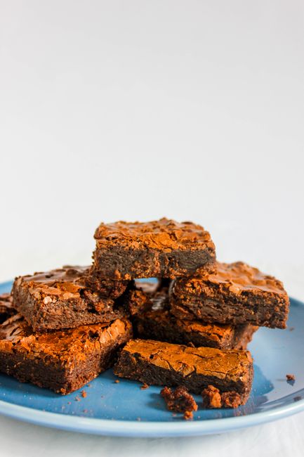 A stack of mouth-watering homemade chocolate brownies on a blue plate.