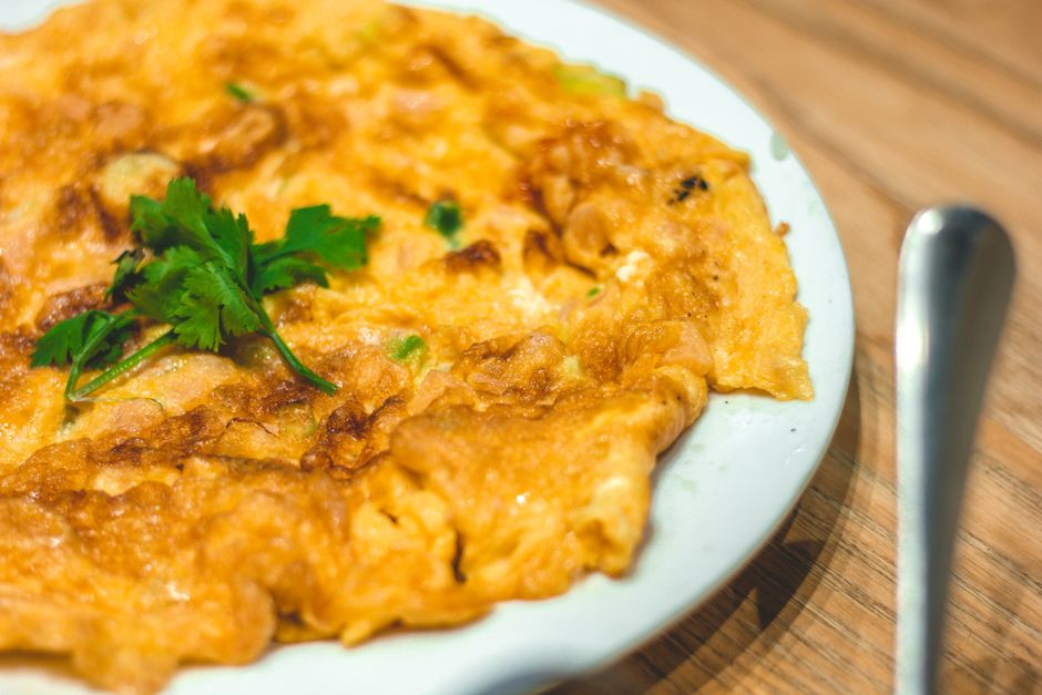 A mouthwatering Taiwanese omelet garnished with fresh cilantro, perfect for Asian cuisine enthusiasts.