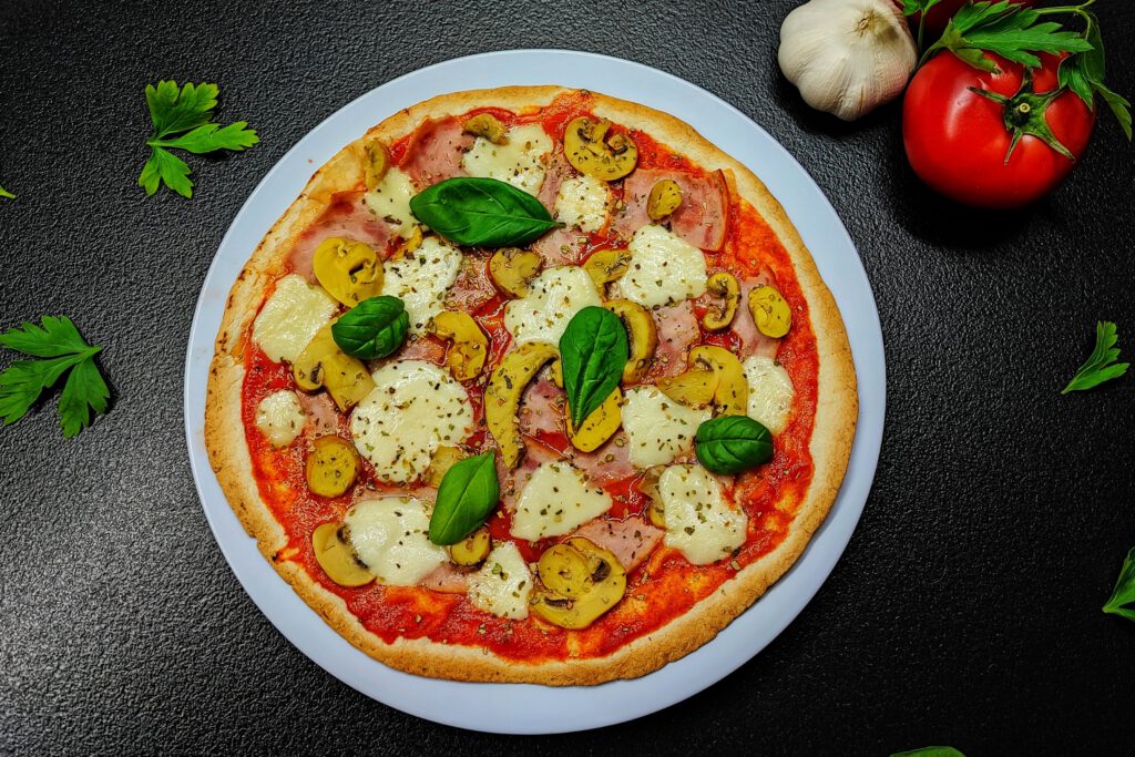 Top-down view of a gourmet mushroom and cheese pizza garnished with basil, showcasing fresh ingredients.