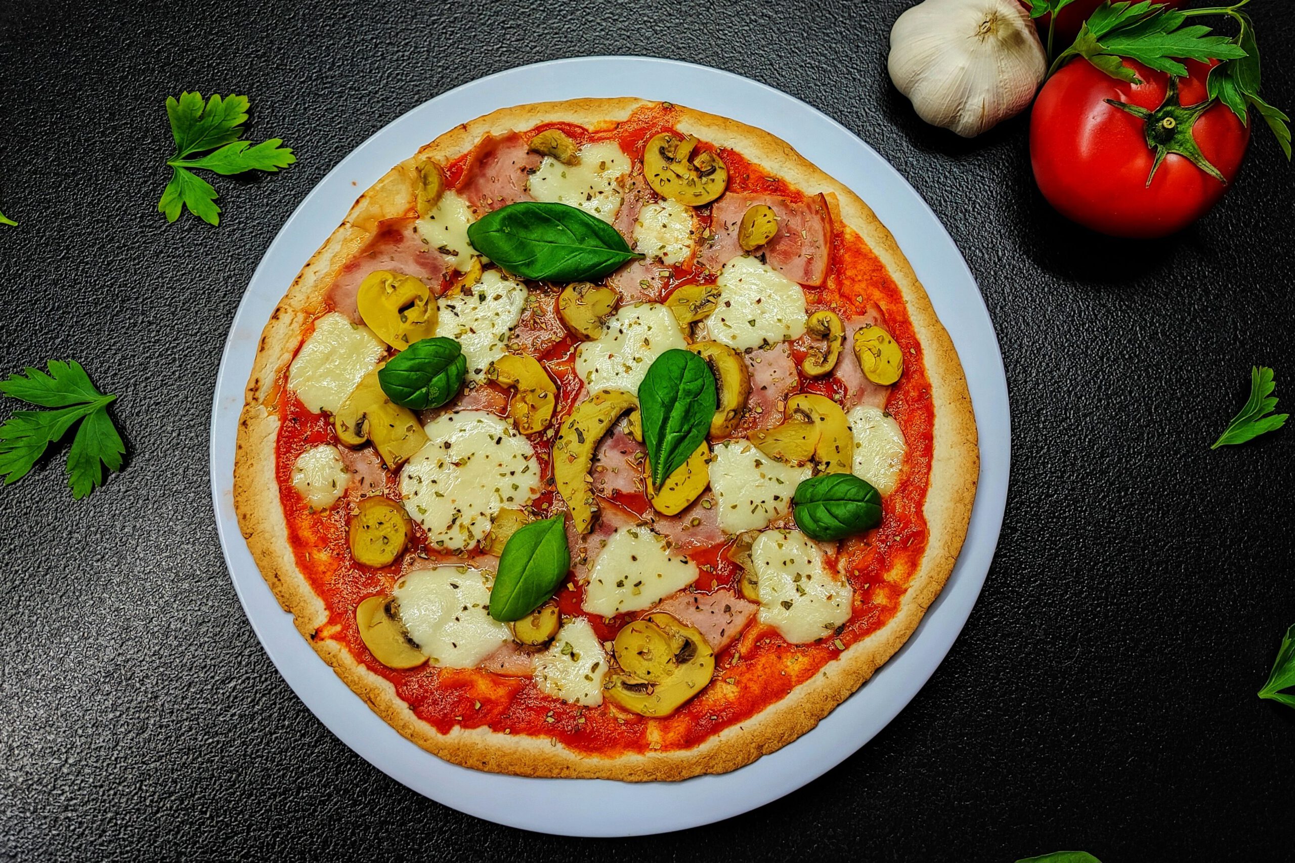 Top-down view of a gourmet mushroom and cheese pizza garnished with basil, showcasing fresh ingredients.