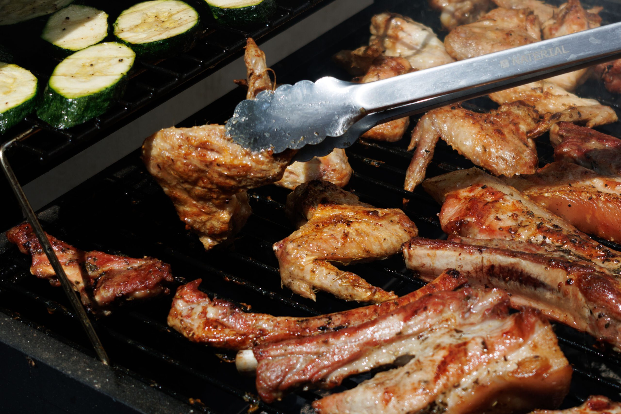 Marinaden. Grill- und Barbecue 1x1 Juicy meat and zucchini being grilled on a barbecue under the summer sun.