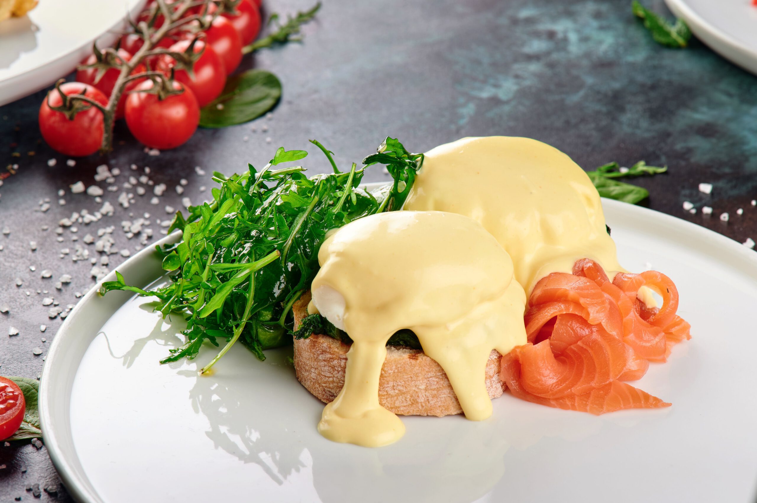 Sauce Hollandaise für Feinschmecker Close-up of eggs benedict with smoked salmon and fresh greens on a white plate.